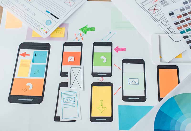 Top view of color circle and sketches of mobile user experience design on wooden table