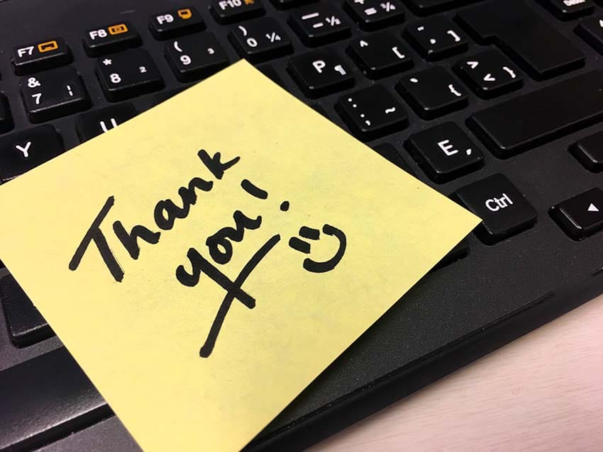 Thank you handwritten note on computer keyboard with smiley face